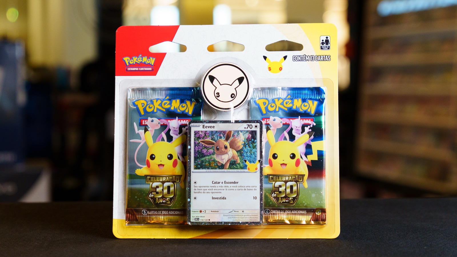 Blister da Celebração de 30 Anos de Pokémon com dois pacotes de booster, moeda do Pikachu e carta promocional do Eevee