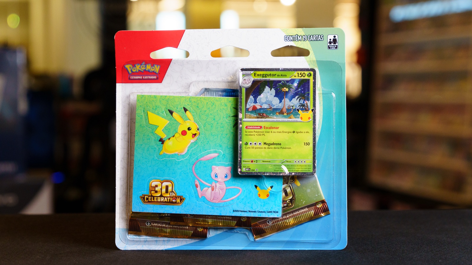 Blister triplo da Celebração de 30 Anos de Pokémon com carta do Exeggutor de Alola e adesivos do Pikachu e do Mew
