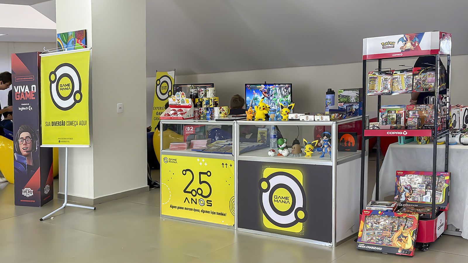 Estande da Game Mania montado na 4ª Feira de Cursos da UFSC Joinville, com produtos Pokémon TCG em destaque