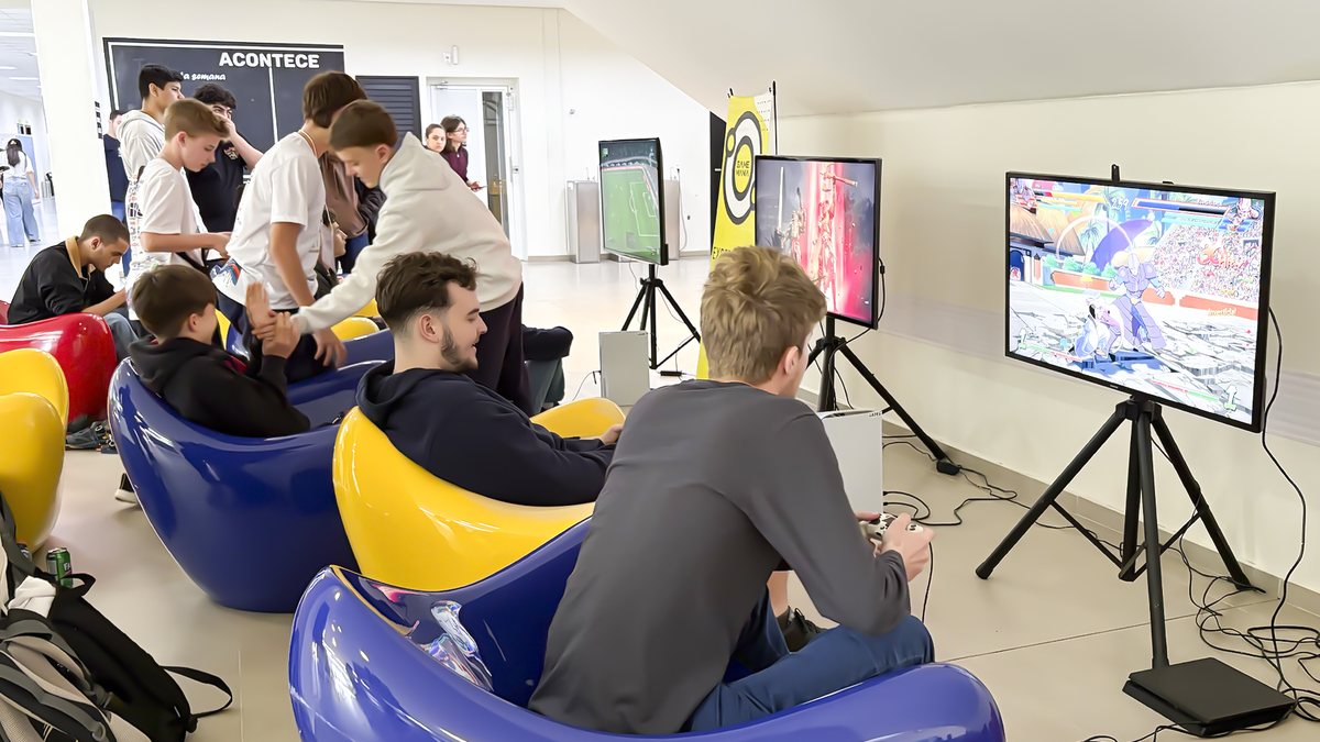 Estudantes jogando em consoles e bean bags no espaço gamer gratuito montado na Feira de Cursos da UFSC Joinville