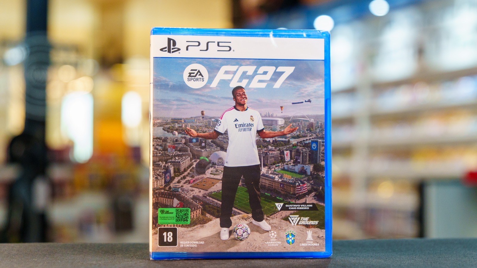 Mídia física de EA SPORTS FC 27 para PlayStation 5 sobre o balcão de uma loja Game Mania