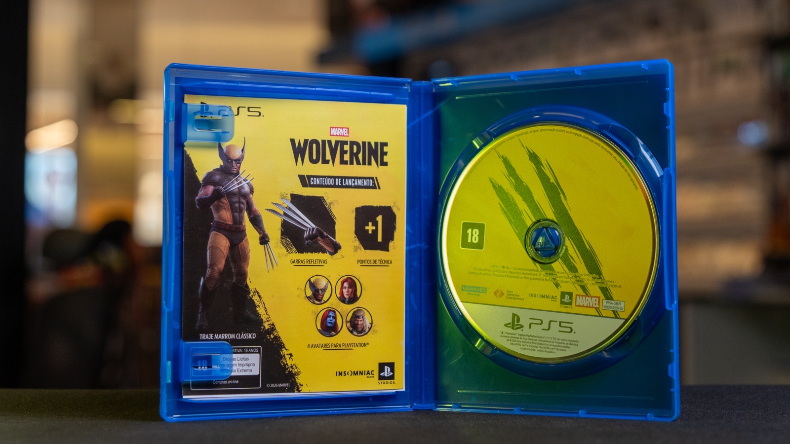 Caixa de Marvel's Wolverine aberta, mostrando o encarte com os bônus de lançamento e o disco do jogo