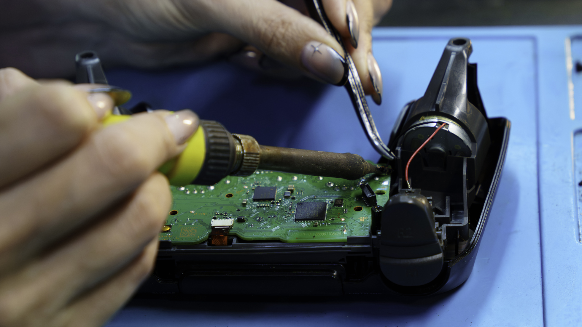 Técnico da Game Mania soldando componentes na placa de um controle