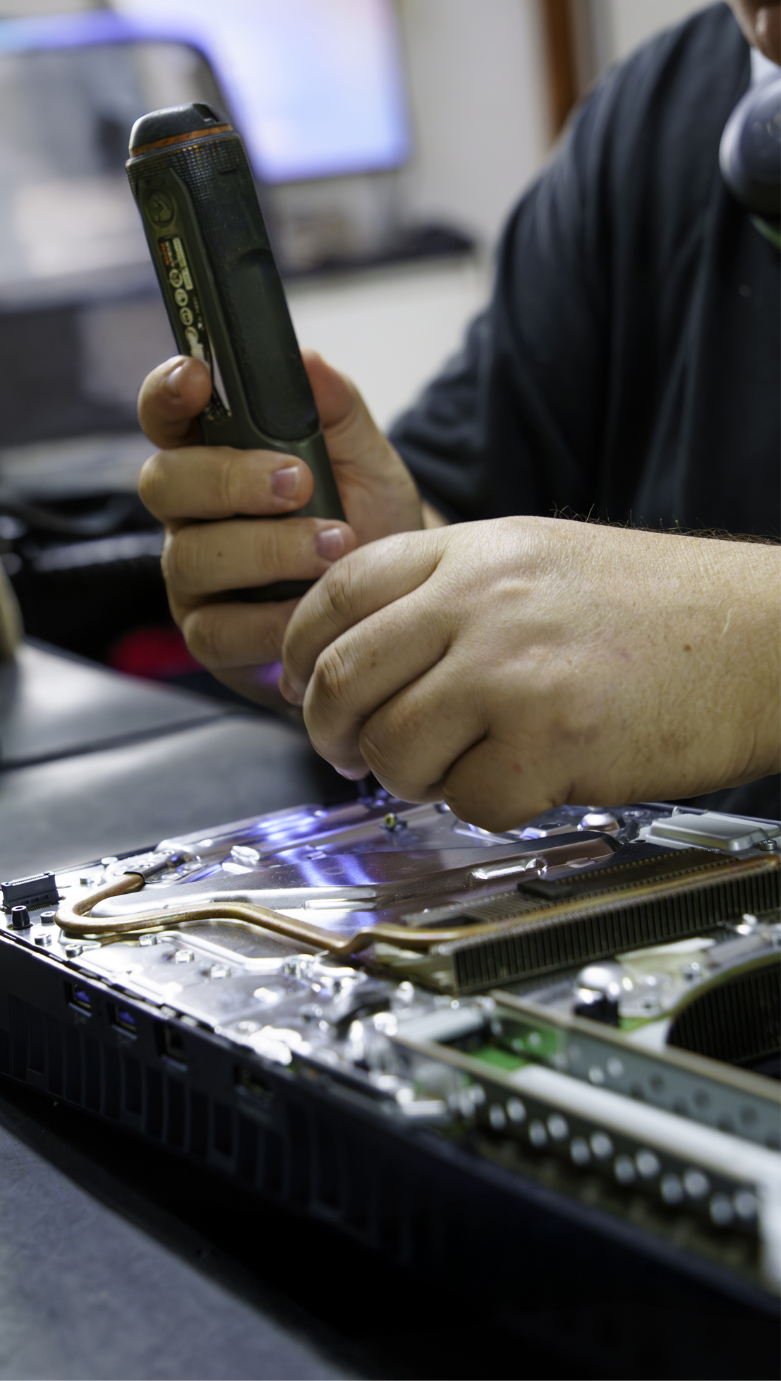 Técnico da Game Mania realizando manutenção interna em um console