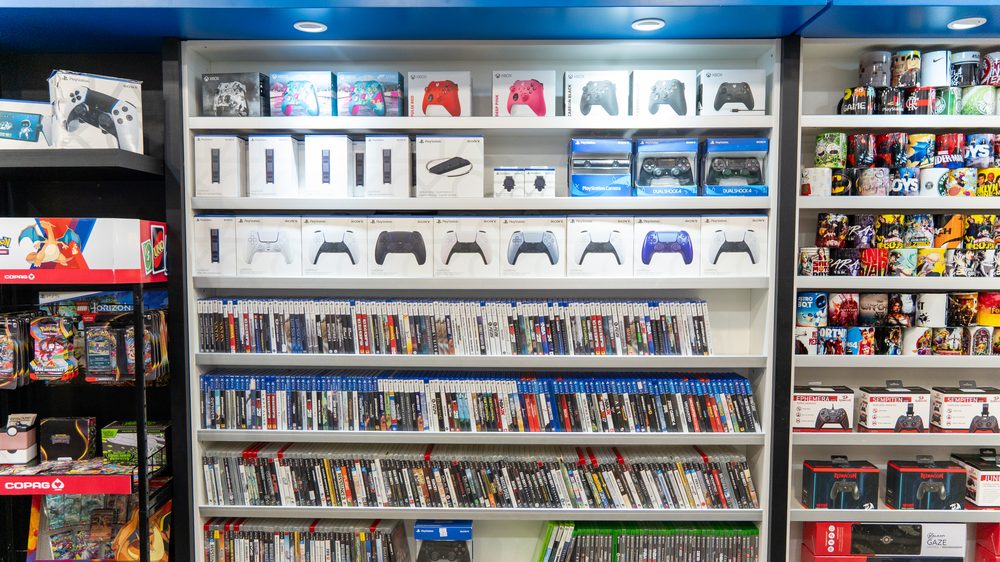 Prateleiras de consoles, controles e jogos na loja Game Mania do Giassi América